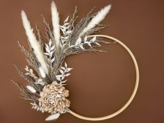 a circular wreath with dried flowers and leaves on a brown background is featured in this image