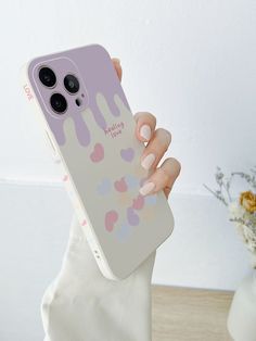 a woman holding up her phone case with hearts on the front and bottom, while she holds