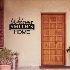 a welcome sign is on the side of a building with potted plants in front of it