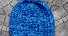 a blue knitted beanie sitting on top of a tile covered floor next to a pair of scissors