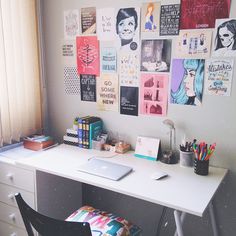 a white desk topped with a laptop computer and lots of pictures on the wall behind it