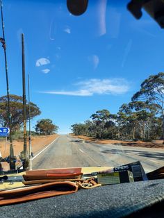 a view from the inside of a vehicle looking at an empty road with trees in the background