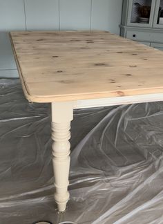 a wooden table sitting on top of a tarp covered floor next to a cabinet