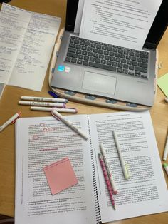 an open laptop computer sitting on top of a desk next to notebooks and pens