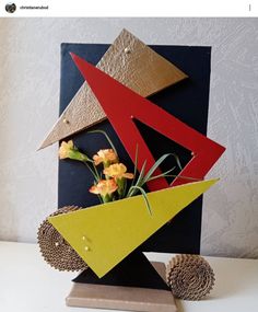 a sculpture made out of cardboard with flowers in the center and an arrow on top