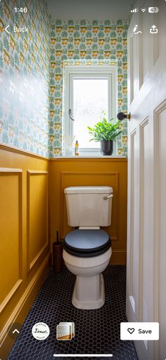 a small bathroom with a toilet and yellow wallpaper on the walls, along with a potted plant