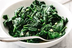 a white bowl filled with spinach and greens