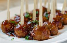 some meatballs with toothpicks in sauce and garnish on a white plate