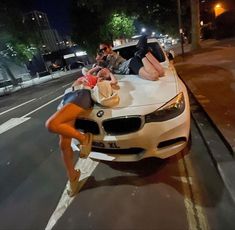 two people laying on the hood of a car