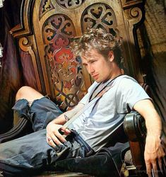 a young man sitting on top of a wooden chair