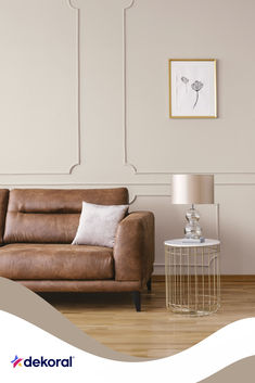 a living room with a brown leather couch and white wall art on the side table