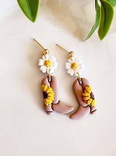 two sunflowers are hanging from the ear hooks on a pair of brown and white earrings