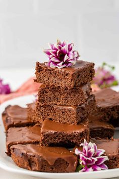 a stack of chocolate brownies on a white plate with flowers in the middle and one piece cut out