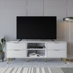 a flat screen tv sitting on top of a white entertainment center next to a potted plant