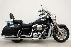 a black and silver motorcycle parked in front of a white wall with no one on it