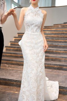 a woman standing in front of some stairs wearing a white dress