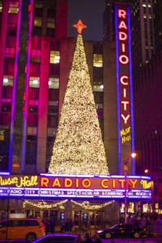 the radio city christmas tree in front of radio city music hall is lit up at night