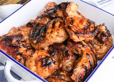 a blue and white bowl filled with chicken wings on top of a checkered table cloth