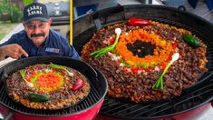 a man sitting in front of two large pizzas on top of a bbq