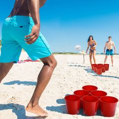 two people playing frisbee on the beach with red cups in front of them