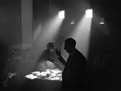 a man standing in front of a table with food on it and people sitting around