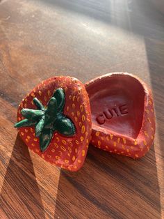 two plastic strawberries sitting on top of a wooden table