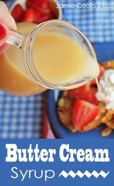 a person is pouring some liquid onto waffles with strawberries on the side