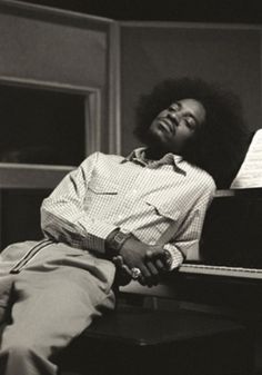 a man laying on top of a piano next to a window