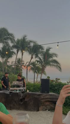 two people sitting at a table with wine glasses in front of them and palm trees