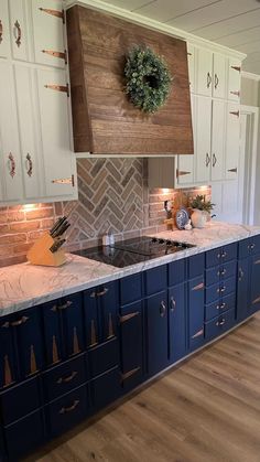 a kitchen with blue cabinets and white counter tops, wood flooring and a wreath on the wall