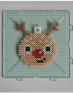 a cross stitch christmas ornament hanging on a wall in the shape of a reindeer