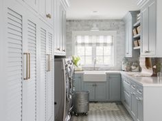 a kitchen with blue cabinets and white counter tops is pictured in this image, there is a laundry basket next to the washer and dryer