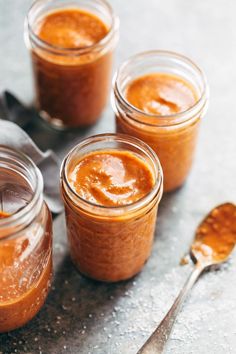 three jars filled with peanut butter on top of a table next to two spoons