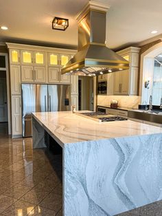 a large kitchen with marble counter tops and an island in front of a stove top oven