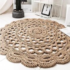 a large round rug on the floor next to a cactus plant and other items in a white room