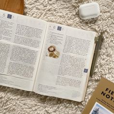 an open book sitting on top of a white rug next to a remote control and other items