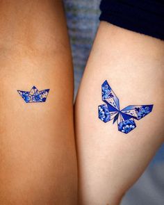 two women's legs with tattoos on them, one is blue and the other has a butterfly