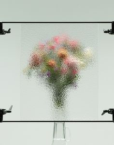 a vase filled with lots of flowers on top of a glass table covered in water