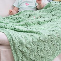 a baby sitting on a couch with a green blanket