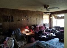 a living room filled with lots of furniture next to a wooden paneled wall and window