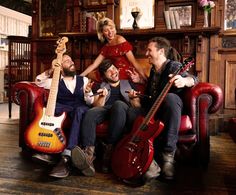 a group of people sitting on top of a red chair with guitars in front of them