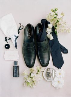 a pair of shoes, tie, and other accessories laid out on a white surface