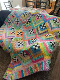 a multicolored quilt sitting on top of a couch next to a wooden table