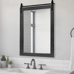 a bathroom sink sitting under a mirror next to a white counter top with two faucets