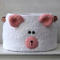 a white basket with pink ears on the top and bottom is sitting on a shelf