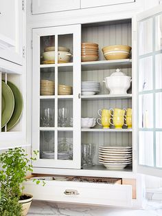 a kitchen with white cabinets and dishes in it