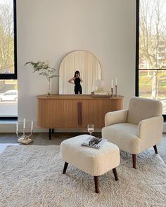 a living room with two chairs and a table in front of a large window that has a mirror on it