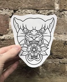 a hand holding up a sticker with an image of a tiger's head