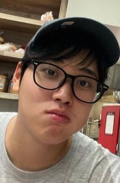 a young man wearing glasses and a baseball cap is making a face at the camera