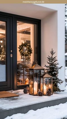 two lanterns are sitting on the porch in front of a house with christmas wreaths and pine cones